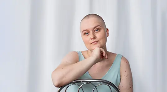 An acute lymphoblastic leukemia patient poses with their hand on their chin.