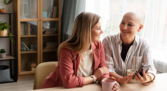 An acute lymphoblastic leukemia patient sits and talks with their friend over coffee.