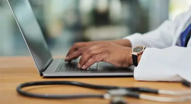 A doctor types on a computer keyboard.